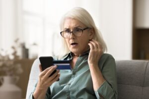Senior woman reading tips to avoid scams on her phone in Yukon, OK